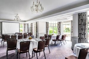 a conference room with tables and chairs and a projection screen at Woodlands Park Hotel in Cobham