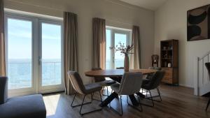 a dining room with a table and chairs and windows at Residentie De Zeester | De Wulk in Scherpenisse