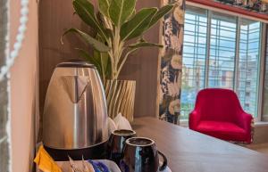 a coffee maker on a table with a red chair at The Botanika Suites in New Town