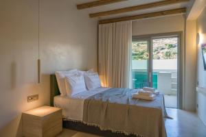a bedroom with a bed and a large window at Lithos Luxury Suites in Tinos +114 photos