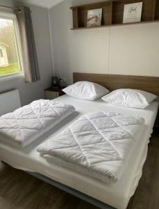 a bed with white sheets and pillows in a bedroom at SimpleStayHolland in Westerland