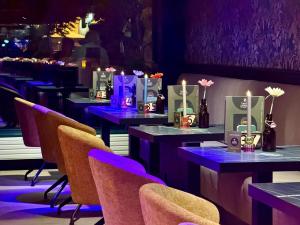 a row of tables in a restaurant with purple lighting at Stadshotel Tante Annie's in Oldenzaal +2 photos