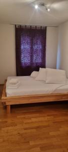 a bed in a room with a purple window at Sofia Apartment - Aare Jungfrau AG in Wilderswil