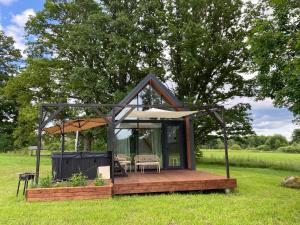 a small house with a deck in the grass at Atpūtas vieta Kannas in Tropmači