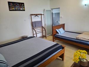 a room with two beds and a chair at Sunset Inn in Kandy