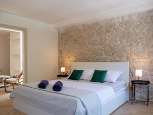 a bedroom with a large white bed and a stone wall at Seafront Stone House Sajbel in Novigrad Dalmatia
