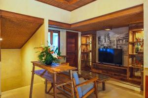 a living room with a table and a tv at Rama Phala Resort & Spa in Ubud