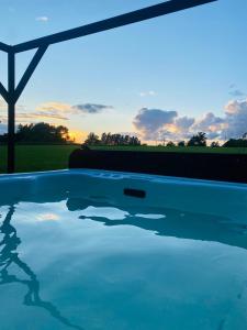 a swimming pool with a sunset in the background at Atpūtas vieta Kannas in Tropmači
