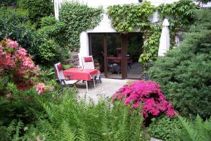 a garden with a red table and chairs and flowers at Feriendomizil Bockelmann in Bad Bevensen