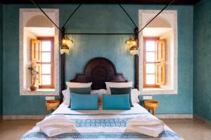 a bedroom with a bed with blue walls and two windows at Daba Village in Marrakesh