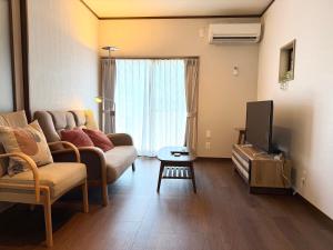 a living room with a couch and a tv at かみくまハウス in Kumamoto