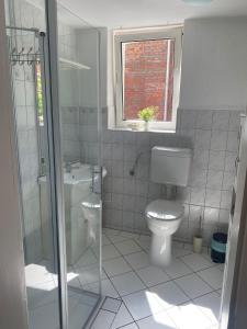 a white bathroom with a toilet and a window at Ferienwohnung am Oechsenberg in Unterbreizbach