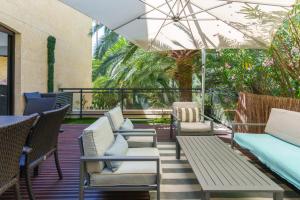 a patio with chairs and tables and an umbrella at Festival de Cannes résidence de luxe piscine tennis in Vallauris
