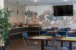 un restaurant avec des tables et des chaises et un bar dans l'établissement The Originals Boutique, Actuel Hôtel, Saint-Etienne Aéroport, à Andrézieux-Bouthéon