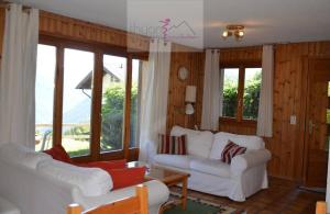 a living room with two white couches and windows at Chalet Zou Derri 3 in Les Collons