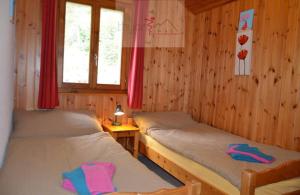 two beds in a room with wooden walls at Chalet Zou Derri 3 in Les Collons