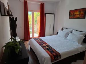 a bedroom with a bed and a window with red curtains at Elysium Retreat in Cinciş
