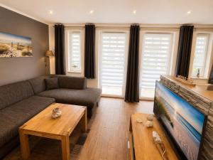 a living room with a couch and a tv at Strandschlösschen in Kühlungsborn