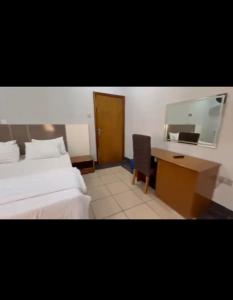 a hotel room with a bed and a desk and a mirror at NBTE Hotels in Kaduna