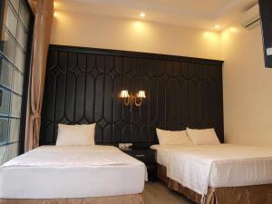 a bedroom with two beds and a black headboard at Ánh Sao in Ha Long
