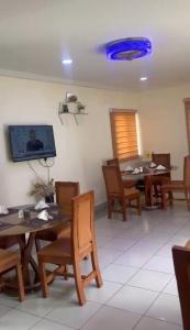 a dining room with tables and chairs and a flat screen tv at NBTE Hotels in Kaduna