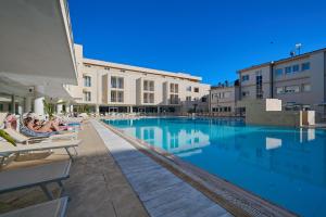 a hotel swimming pool with people sitting in lounge chairs at Hotel Terme Marine Leopoldo II TERME & SPA in Marina di Grosseto