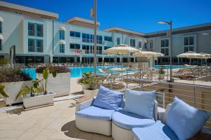 a resort with chairs and umbrellas next to a pool at Hotel Terme Marine Leopoldo II TERME & SPA in Marina di Grosseto