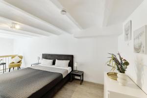 a white bedroom with a bed and a chair at Kenzingen Appartements zur Alten Brauerei in Kenzingen