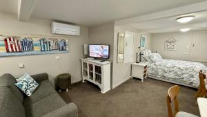 a living room with a couch and a bed at Whitby Studio - Mairangi Bay Beach in Auckland