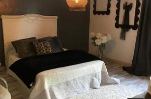 a bed with a black and white blanket and a vase of flowers at Havre de paix in Péreuil
