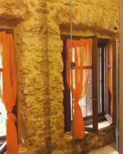 un muro di pietra con finestre e tende arancioni di Niko's Stone Guest House a Plitra