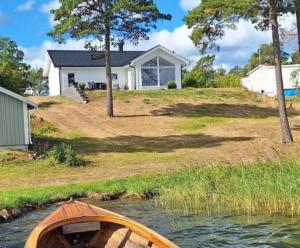 a wooden boat in the water in front of a house at 2 bedroom house with sea view in Mönsterås