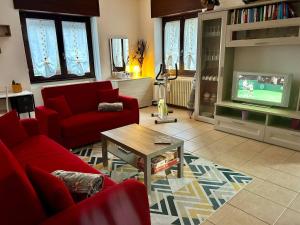 a living room with a red couch and a tv at La Farfalla B&B - Mark&Rosy in Malonno