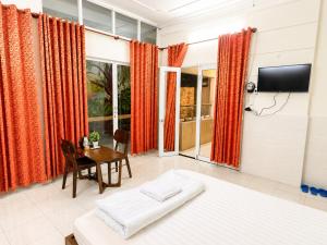 a room with two beds and a table and a television at QN Home in Quy Nhon
