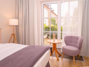 a bedroom with a bed and a chair and a window at BE BIO Hotel be active - Nähe historischer Hafen in Tönning +53 photos
