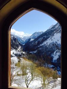 una finestra ad arco con vista su una montagna innevata di Auberge Toison d'Or a Cette-Eygun