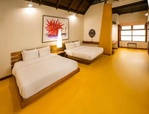 a bedroom with two beds and a yellow floor at Decameron Decalodge Ticuna in Leticia