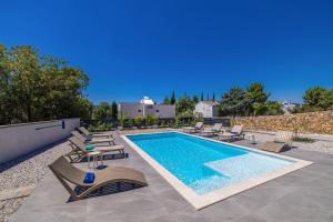 a swimming pool with chaise lounges and chairs around it at Villa ADRIA MOMENTS with private pool in Pinezici