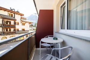 a small table and chairs on a balcony with a window at Hotel Haus am Wald in Arosa