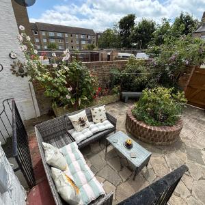 a patio with a couch and tables and flowers at Moat Stays Victorian, Sea View! in Kent