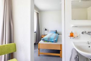 a bathroom with a sink and a bed in a room at Hotel Haus am Wald in Arosa +20 photos
