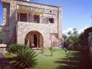 a large stone building with a balcony in a yard at Niko's Stone Guest House in Plytra