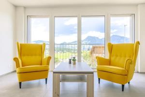 two yellow chairs and a table in front of a window at Stockhorn Apartment - Aare Jungfrau AG in Spiez