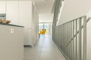 a hallway with a staircase and a yellow chair at Stockhorn Apartment - Aare Jungfrau AG in Spiez +24 photos