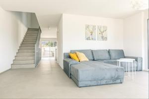a living room with a blue couch and a staircase at Niesen Apartment - Aare Jungfrau AG in Spiez