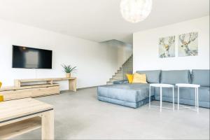 a living room with a blue couch and a tv at Niesen Apartment - Aare Jungfrau AG in Spiez