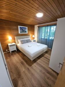a bedroom with a white bed and a wooden wall at Peak Apartment - Aare Jungfrau AG in Grindelwald