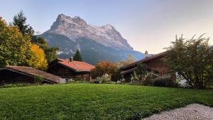 a house in the foreground with a mountain in the background at Apartment Chalet Condor - Aare Jungfrau AG in Grindelwald