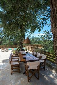a wooden table and chairs under a tree at Villa Praxithea in Lákka +37 photos