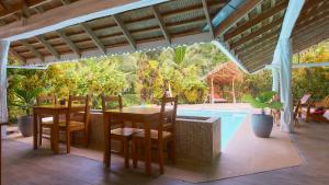 a patio with a table and chairs and a swimming pool at La Rana De Cahuita in Cahuita